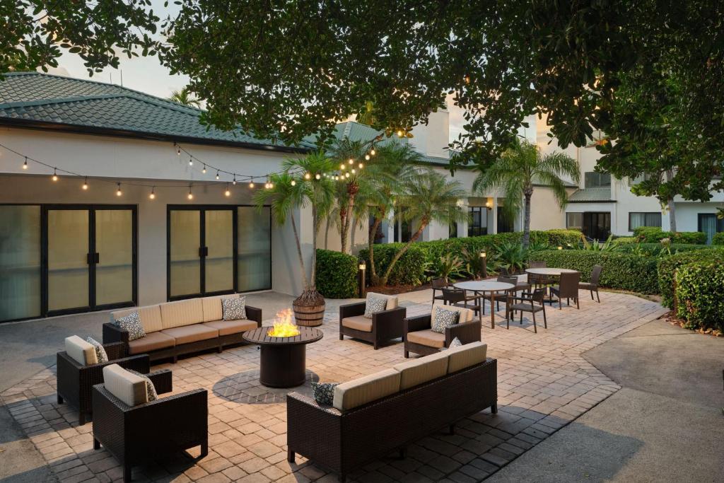 un patio con sofás, mesas, sillas y árboles en Courtyard Miami Airport West/Doral, en Miami