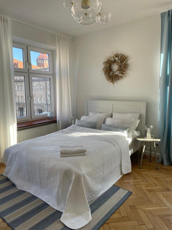 - une chambre avec un lit blanc et 2 serviettes dans l'établissement Apartament w centrum Gdańska, à Gdańsk