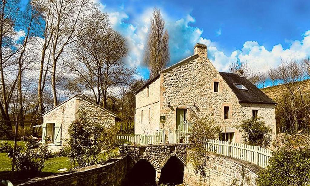 una gran casa de piedra con un puente delante de ella en Les 2 gites des Chambres de Capucine en Carcagny