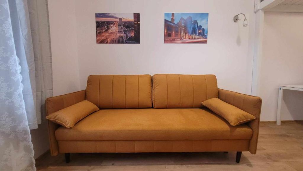 a couch in a room with two pictures on the wall at City Center Gdańska Apartment in Łódź