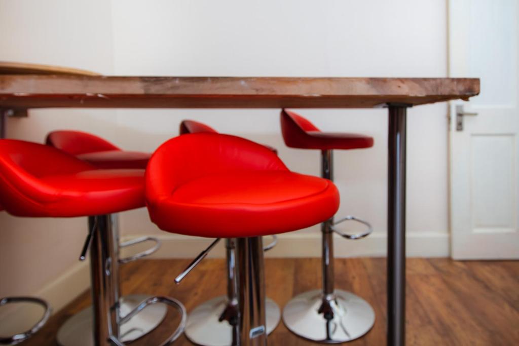 a group of red bar stools under a table at Colourful&Bright Apartment by Carlton Hill in Edinburgh