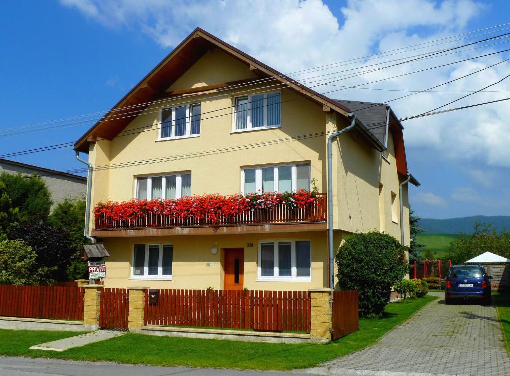 a yellow house with red flowers on a balcony at Apartment Skurčák in Zuberec