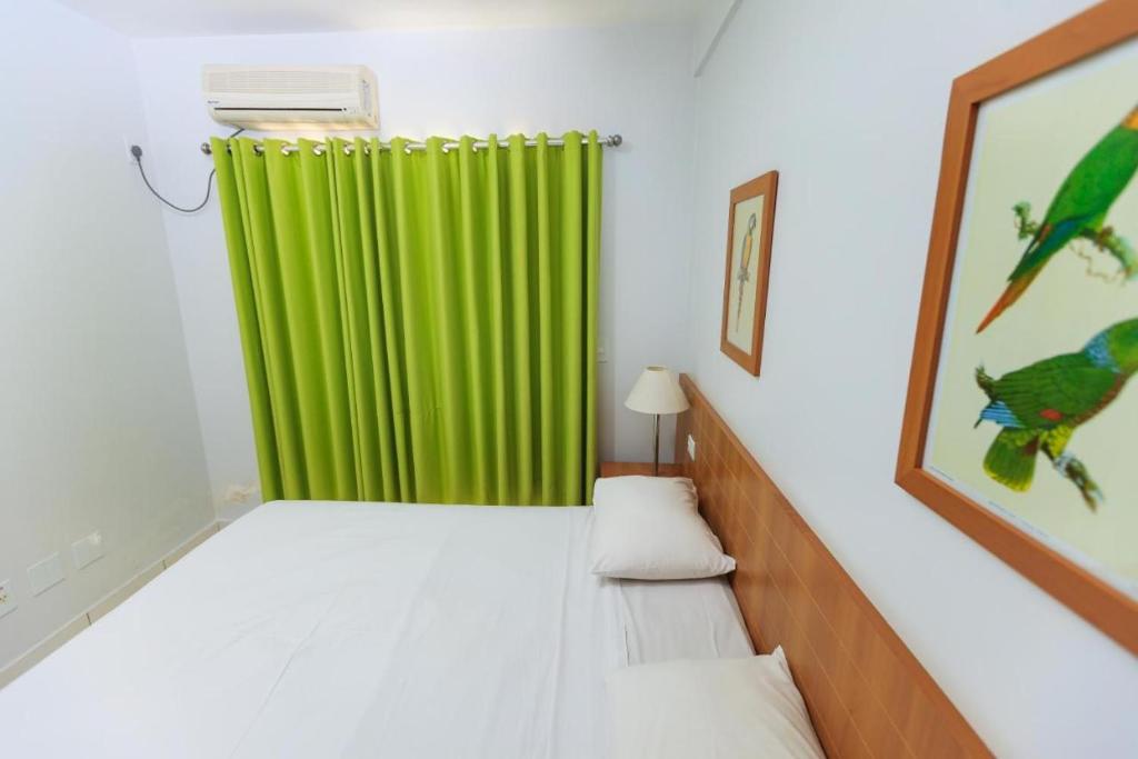 Cette chambre comprend un rideau vert et un lit. dans l'établissement Golden Dolphin Express via Giro ImobTech, à Caldas Novas
