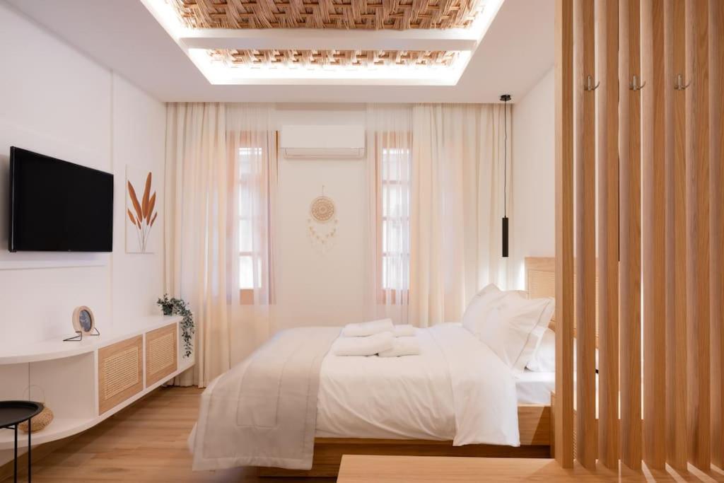 um quarto com uma cama branca e uma televisão em Boutique 27, luxury apartment. em Ioannina