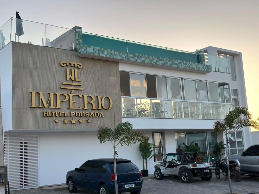a hotel with cars parked in front of it at WL IMPERIO HOTEL POUSADA in Canoa Quebrada