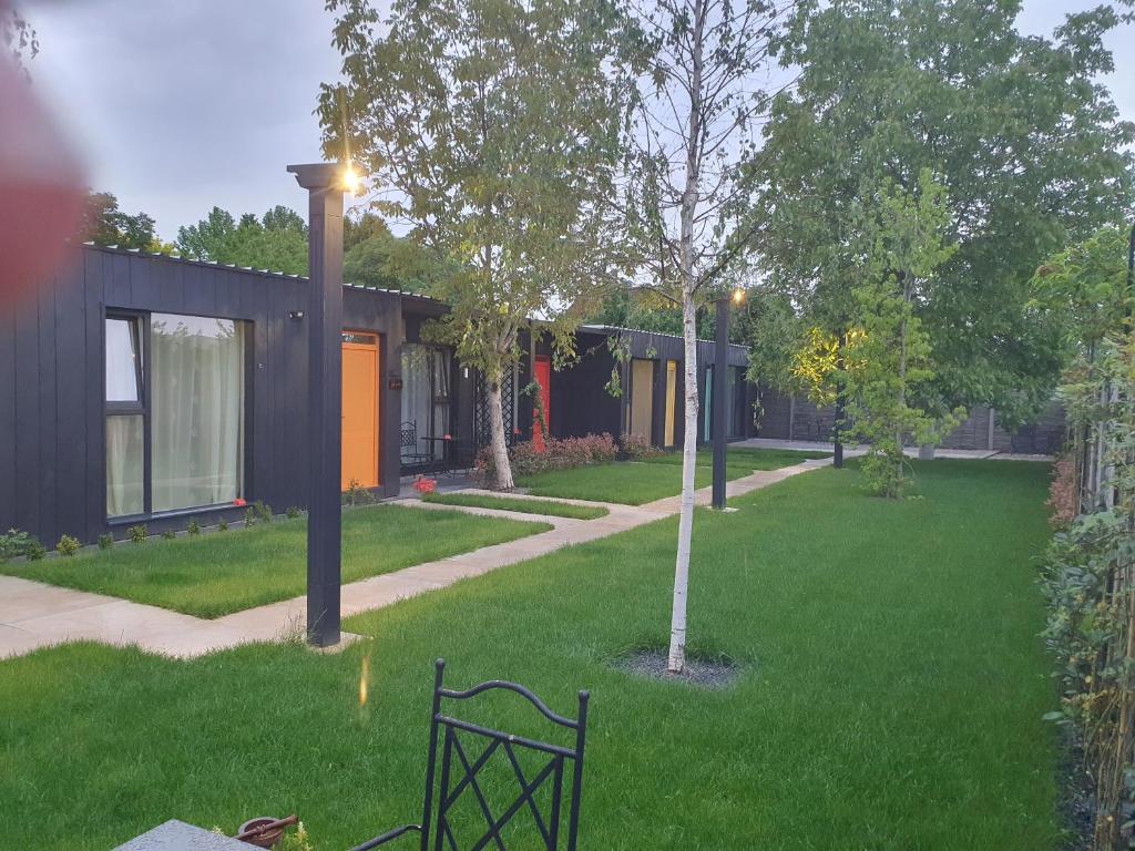 un cortile verde con una panchina di fronte a una casa di Pensiune Arada a Arad