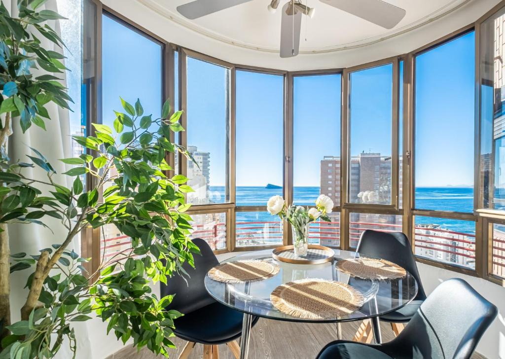een eetkamer met een tafel en stoelen en grote ramen bij Coblanca 5-15-4 Apartment Levante Beach in Benidorm