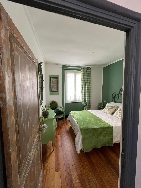 a bedroom with a bed and green walls and wooden floors at LINO'S HOUSE in Sori
