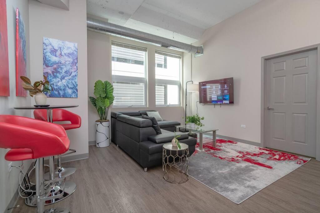 a living room with a black couch and red chairs at McCormick 2br/2ba KING beds suite with gym and optional parking for up to 6 guests in Chicago