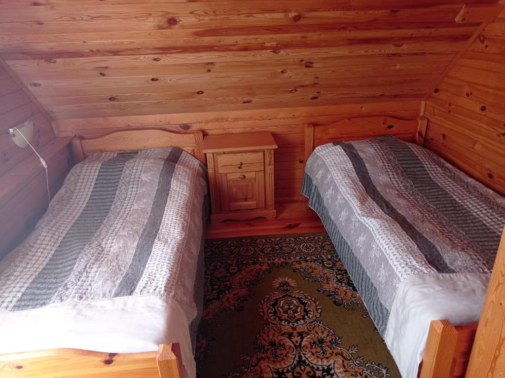 U Czesiuka في Jałowo: سريرين في غرفة بجدران خشبية