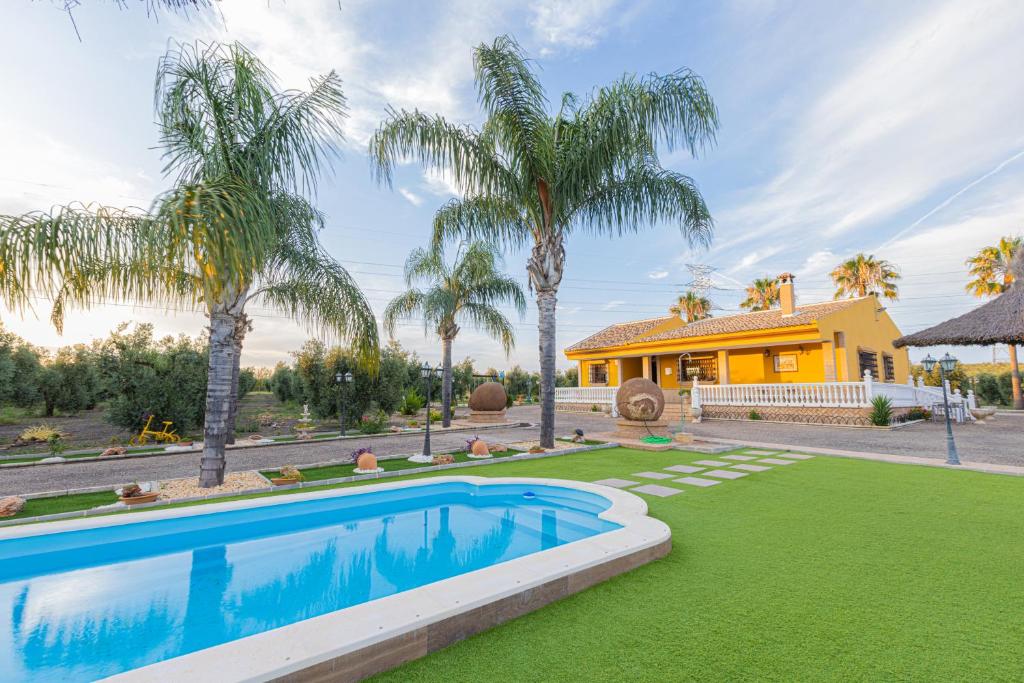 dom z basenem i palmami w obiekcie Casa Rural en el entorno de Doñana w mieście Hinojos