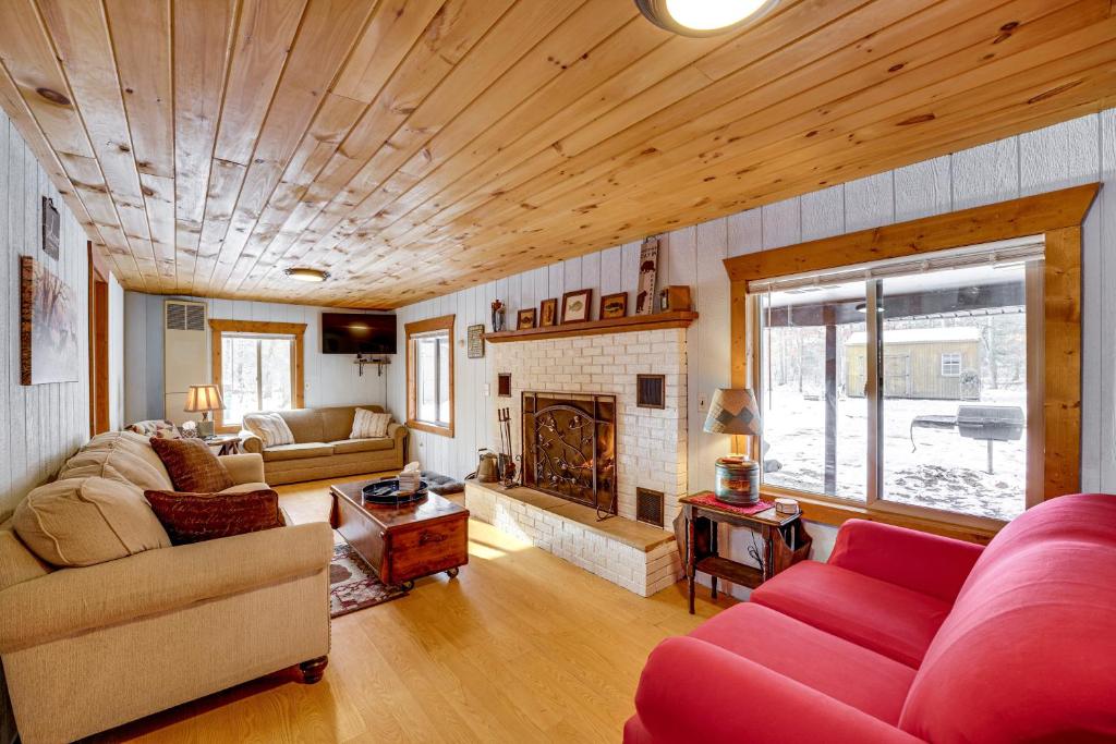 ein Wohnzimmer mit einem roten Sofa und einem Kamin in der Unterkunft Pet-Friendly Irons Cottage about 4 Mi to Sand Lake! in Irons