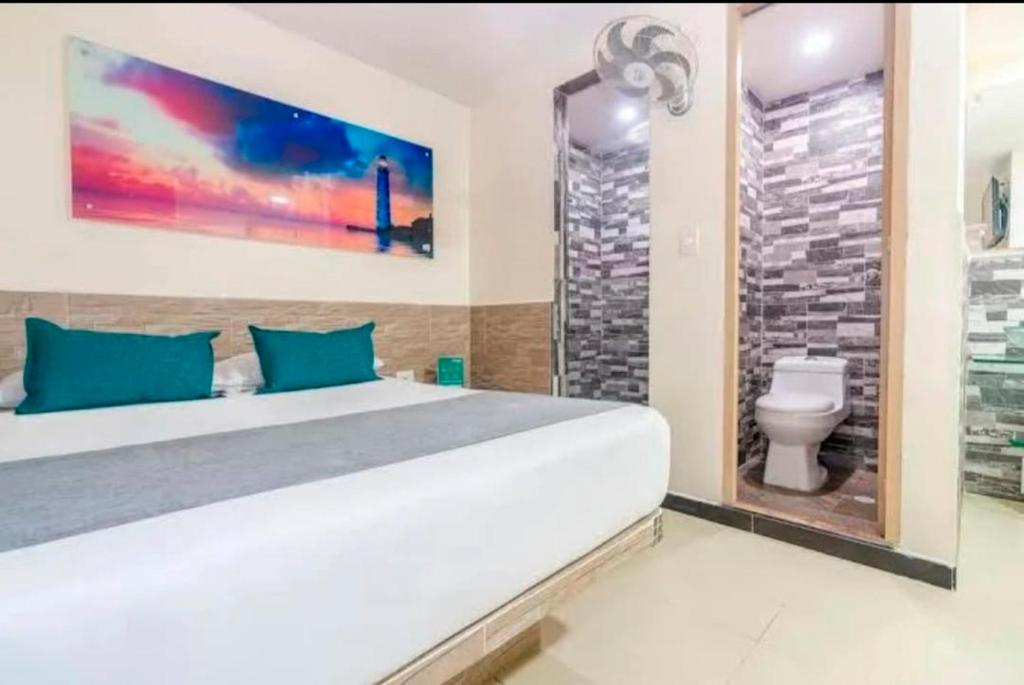 a bedroom with a large white bed and a bathroom at HOTEL CASA GIRARDOT in Medellín