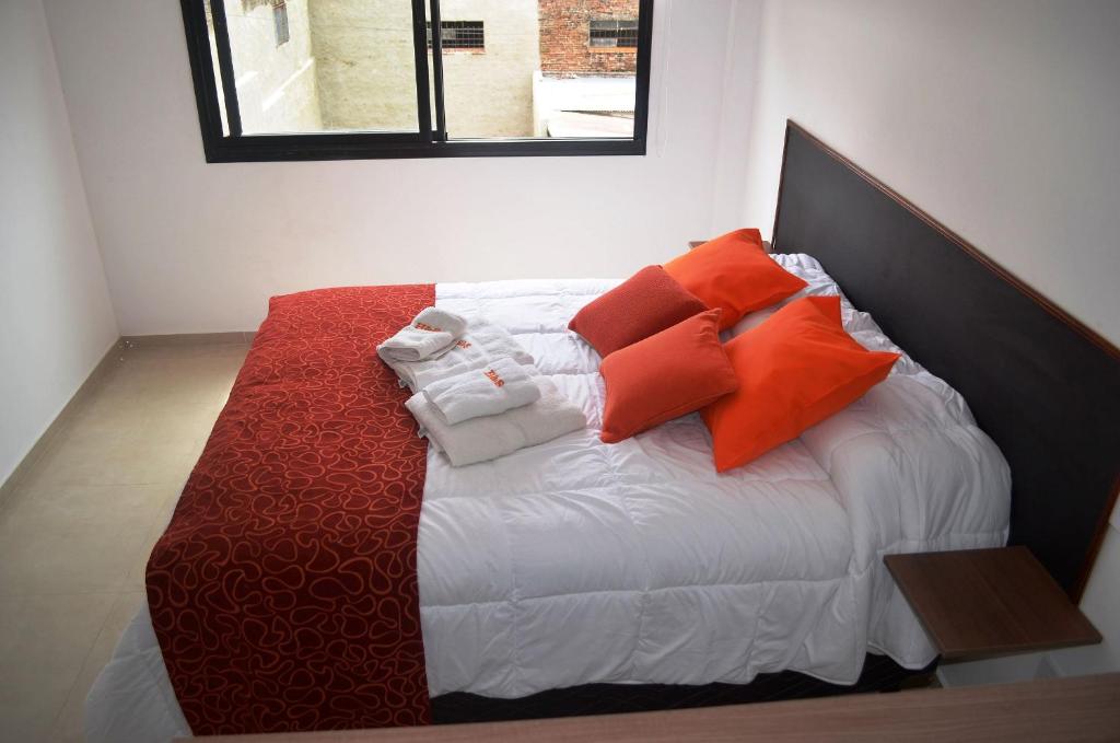House and Suite Premium في سانتا في: سرير عليه وسائد برتقالية وبيضاء