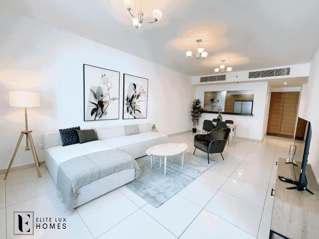 a white living room with a bed and a table at Elite LUX Holiday Homes - Two Bedroom Apartment Metro Nearby in Al Furjan, Dubai in Dubai