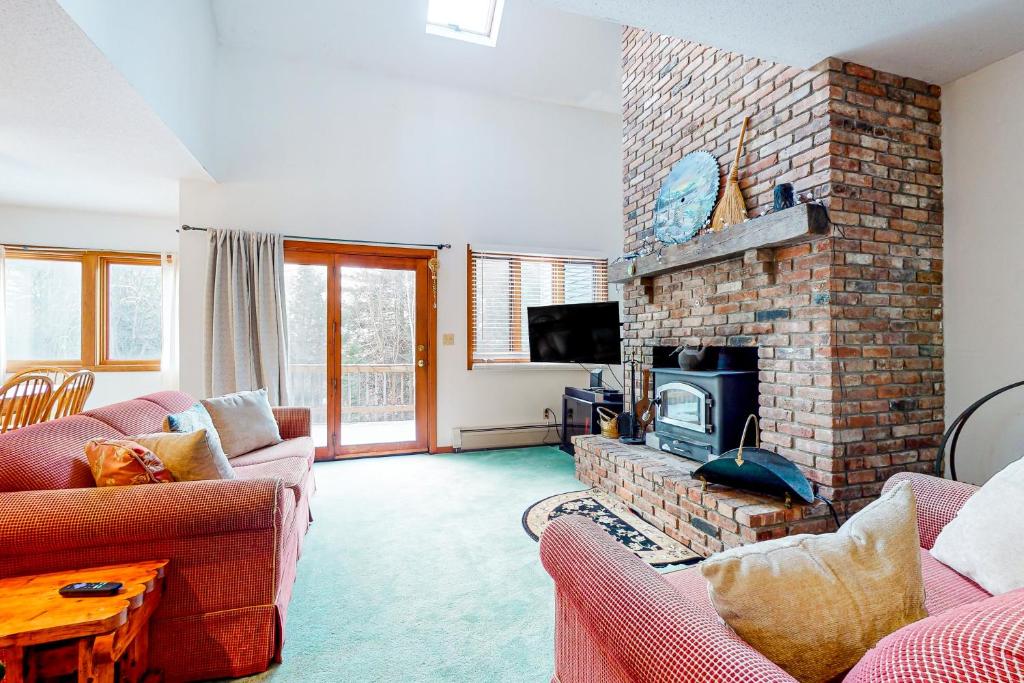 a living room with two couches and a brick fireplace at A Very Vermont Vacation in Jamaica