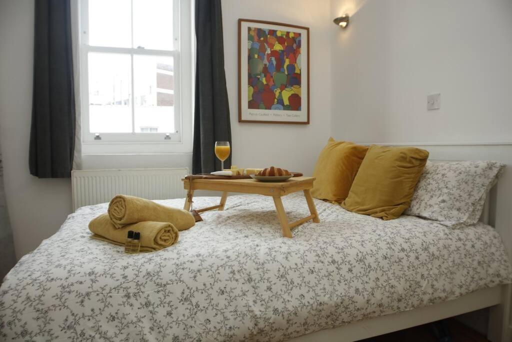 a bed with a table and a glass of wine on it at Very Nice Flat close to Camden Station in London