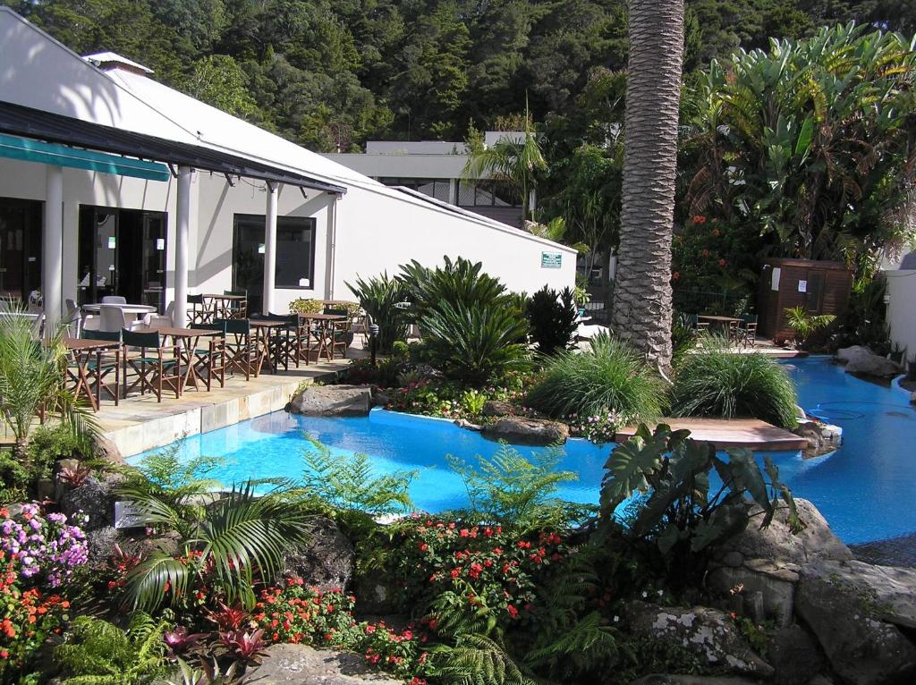 a swimming pool in a garden with flowers and plants at Paihia Pacific Resort Hotel in Paihia