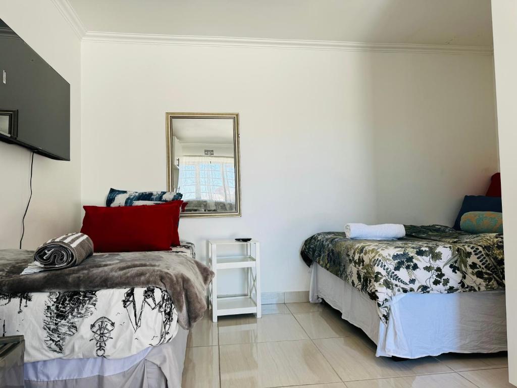 1 dormitorio con 2 camas y espejo en Mila Lodge 2, en Ciudad del Cabo