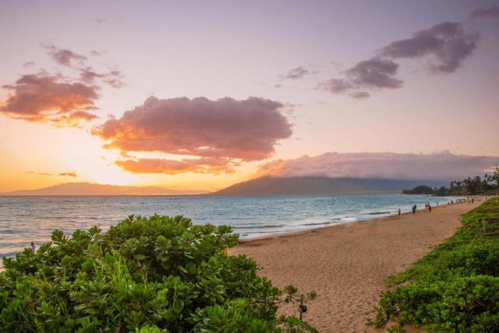 una playa al atardecer con un grupo de personas en ella en Kamaole Beach Club B107 BY Betterstay, en Kihei