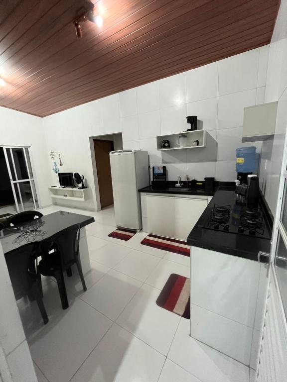 una cucina con elettrodomestici bianchi e piano di lavoro nero di PARAISO DAS AGUAS - CHALÉ a Barra de Santo Antônio