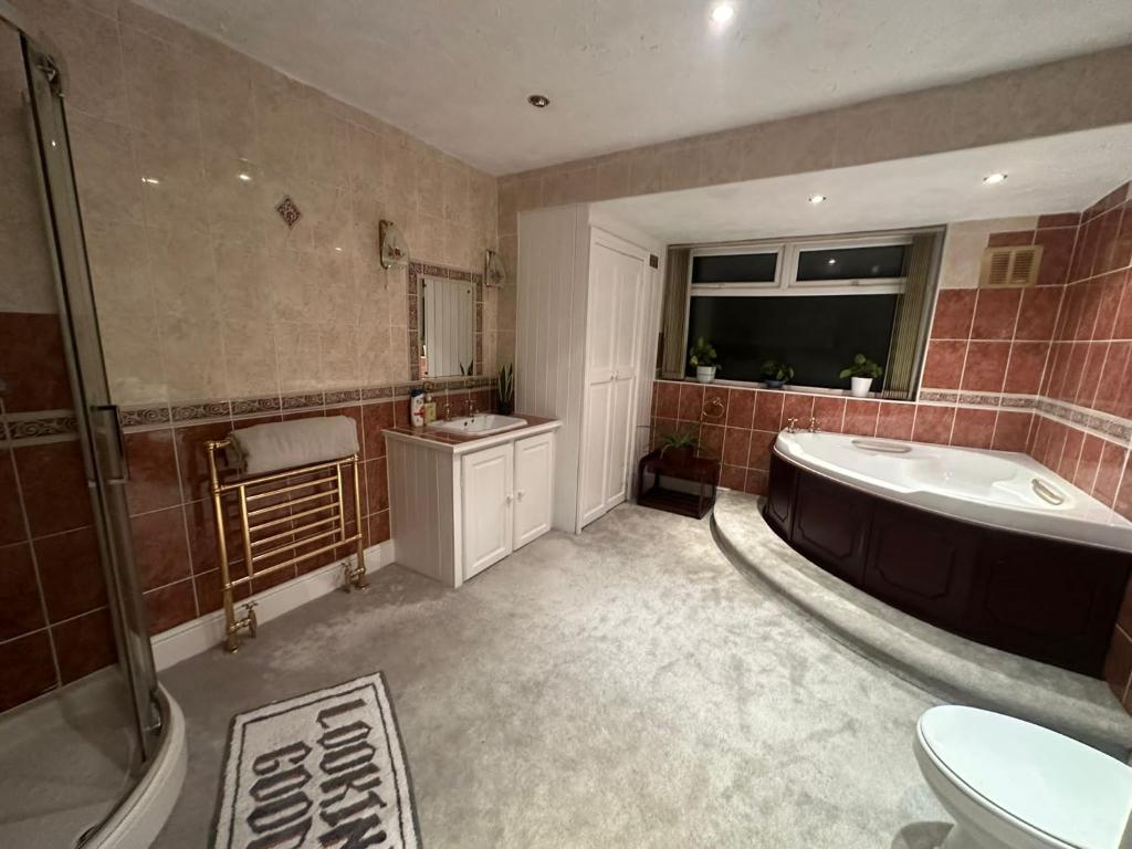 a bathroom with a tub and a sink and a toilet at Large 3 bedroom house in Nottingham