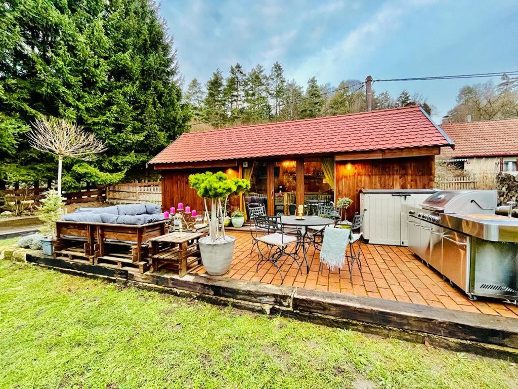 a patio with a couch and a table and a house at Tiny House Všemily in Jetřichovice