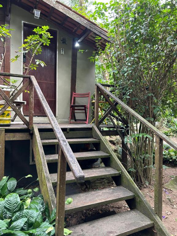 a staircase leading to a house with a red chair at Chalé Ouro Verde in Angra dos Reis
