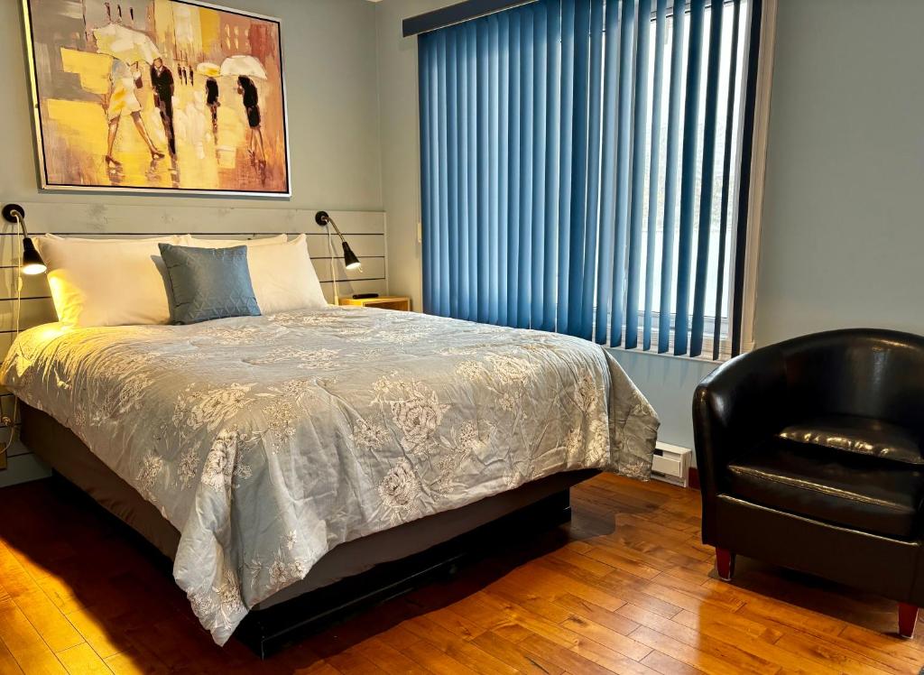 - une chambre avec un lit et une chaise noire dans l'établissement Aux Portes du Soleil, à Baie-Saint-Paul