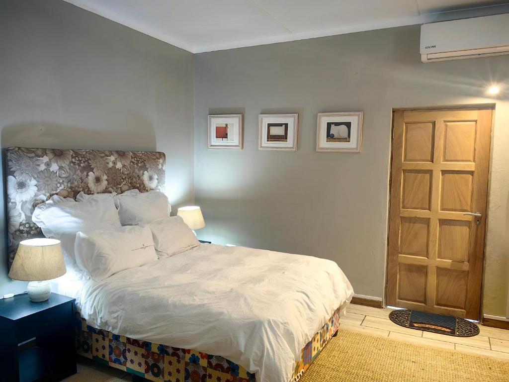 1 dormitorio con 1 cama grande con sábanas blancas en Mitchell Guesthouse, en Pietermaritzburg