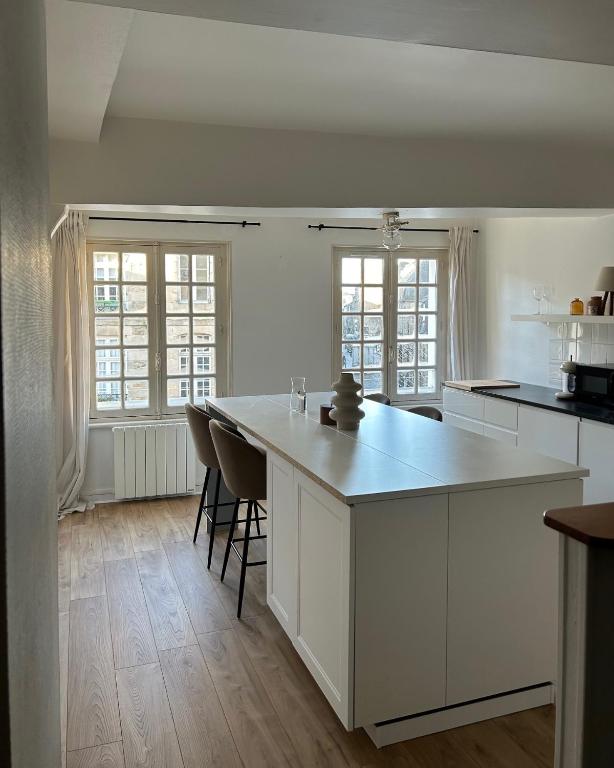 une cuisine avec des placards blancs et un grand îlot dans l'établissement Spacieux appartement au coeur du centre historique de Dinan, à Dinan