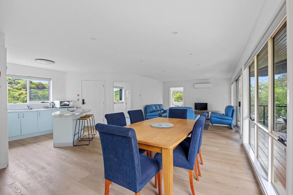 a kitchen and dining room with a wooden table and blue chairs at Sandy Point Beach Escape 2 Bedroom Apartment in Sandy Point