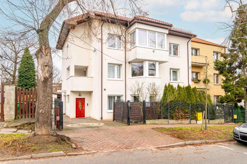 une maison blanche avec une porte rouge dans l'établissement Willa LTC Apartments Orłowo, à Gdynia
