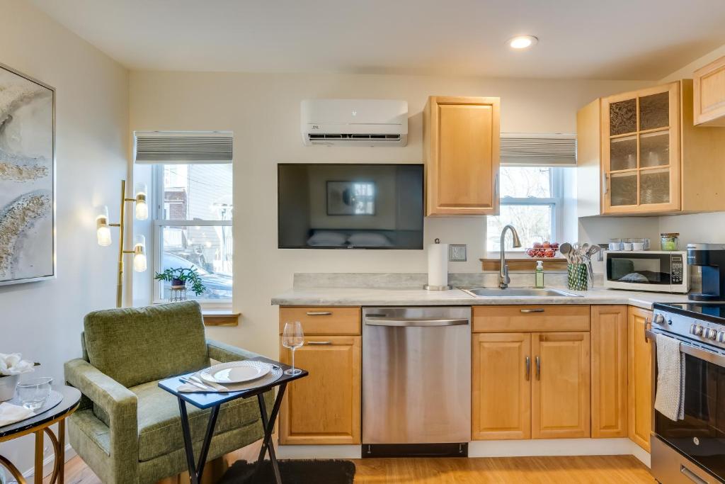 a kitchen with wooden cabinets and a table and a chair at Walkable Downingtown Studio with Spacious Deck in Downingtown