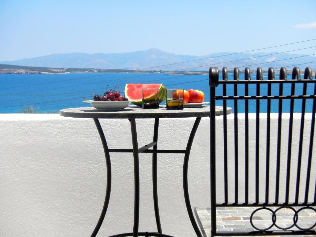 a table with a bowl of fruit and a plate of watermelon at Playera bungalow F sea view in Kolympithres