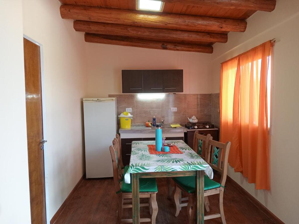 Una cocina con una mesa con sillas y un refrigerador. en Departamento Dharma, en Capilla del Monte