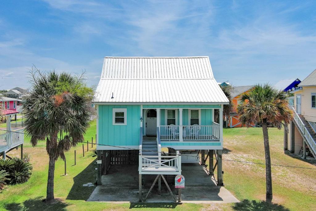 ein blaues Haus mit einem weißen Dach und zwei Palmen in der Unterkunft Bon Vie in Gulf Shores