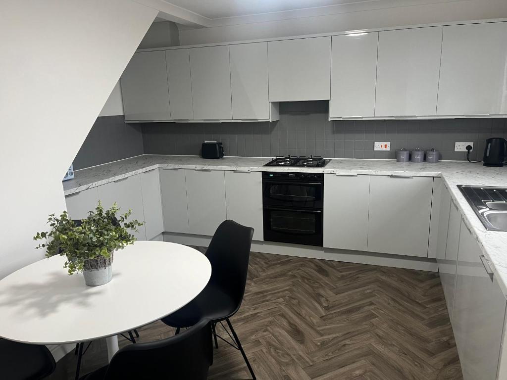 a kitchen with white cabinets and a table with chairs at Duplex Flat Bedworth Town Centre in Bedworth
