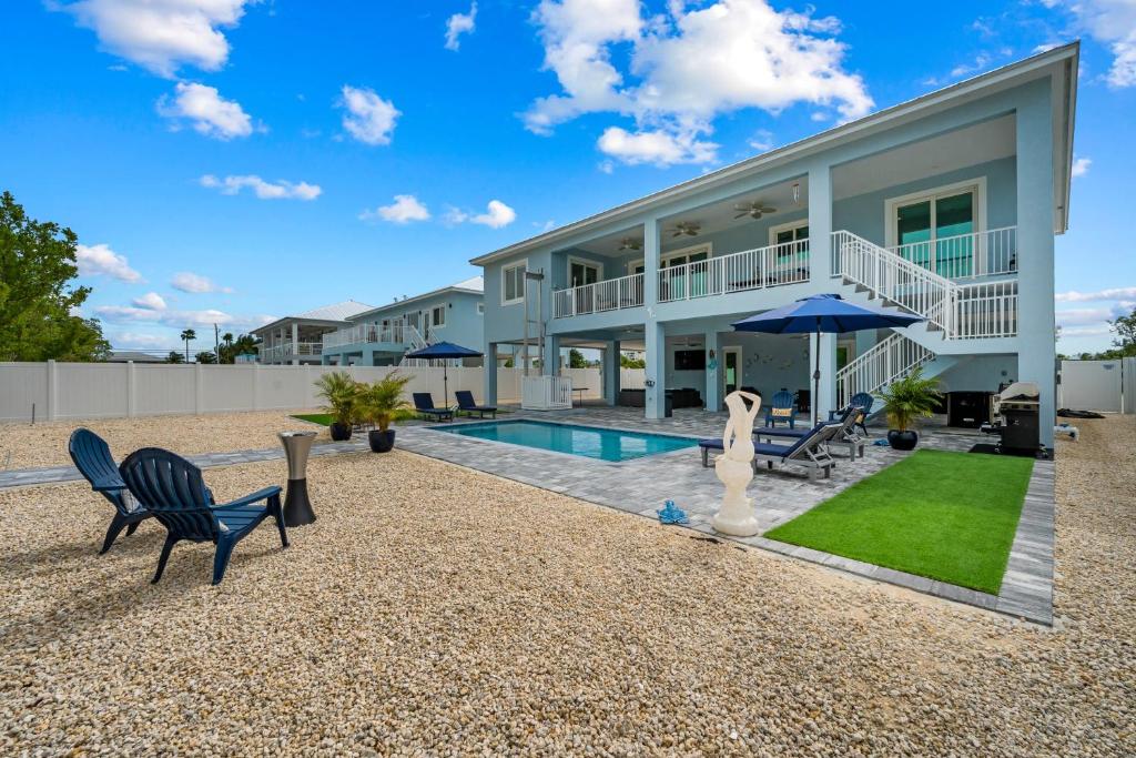 a home with a swimming pool and chairs and a house at Mermaid's Paradise ~ Pool ~ Dock ~ Games ~ Views in Marathon