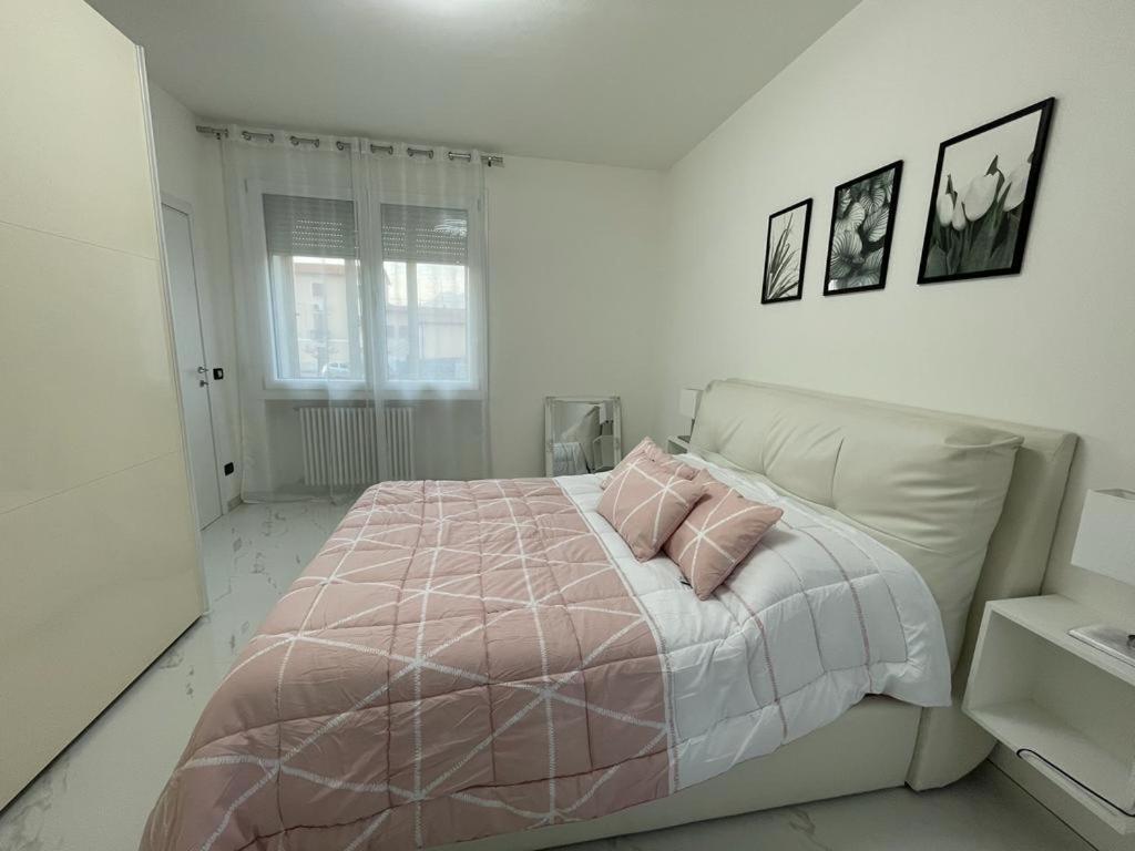 a white bedroom with a bed with two pink pillows at Casa M&N in Thiene
