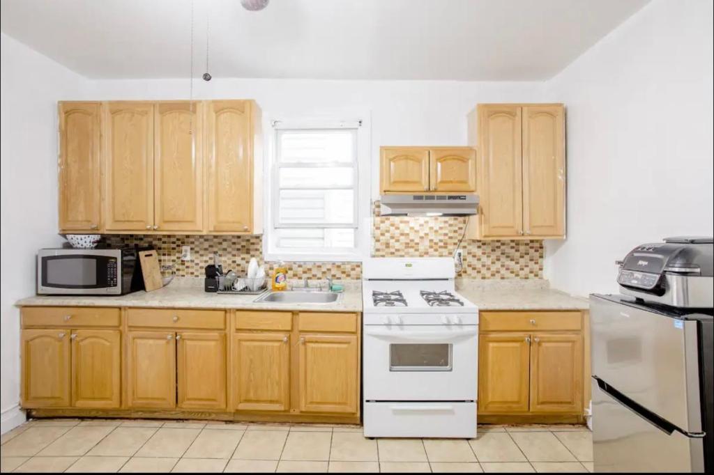 a kitchen with wooden cabinets and a white stove top oven at SUITE DREAMs CARROLL 10 in Paterson