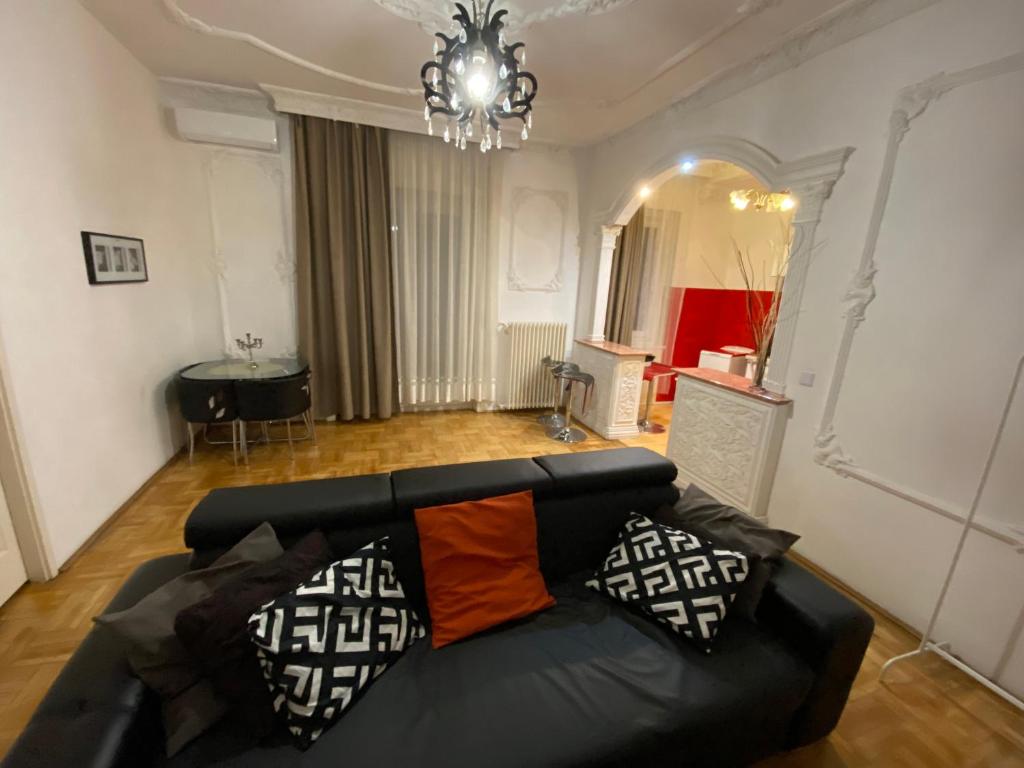a living room with a black couch and a chandelier at HearT of the city 2 bedroms, living rooms, bathrooms, with AC in Budapest