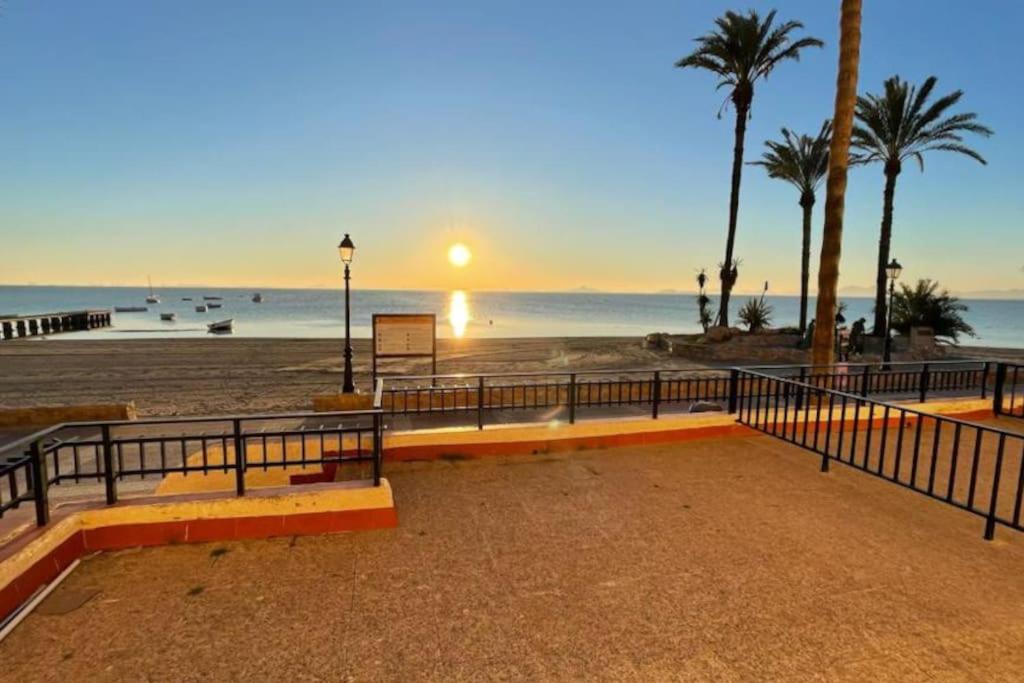 una spiaggia con recinzione, palme e l'oceano di Charming Beachfront apartment a Murcia