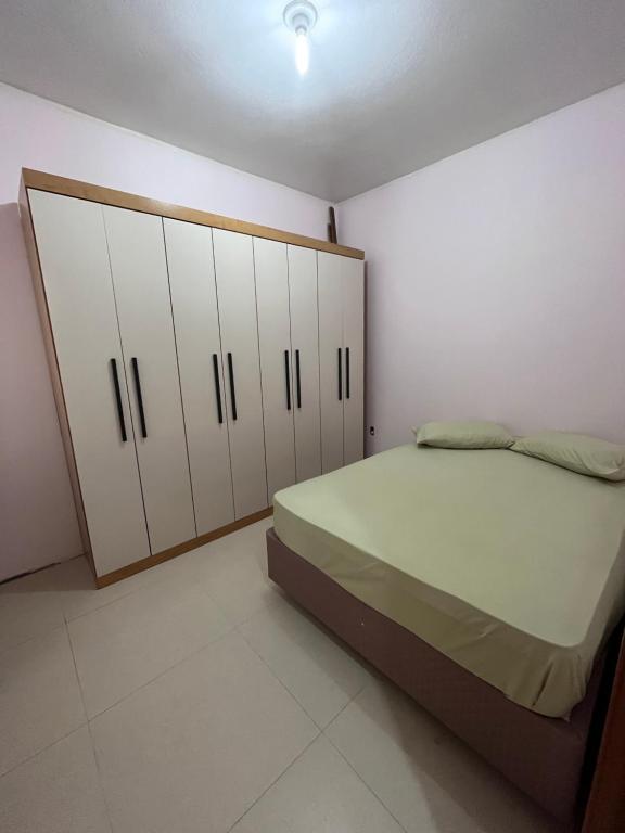 a bedroom with a bed and some white cabinets at Casinha na praia in Imbé