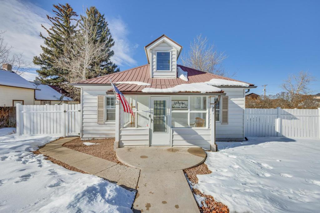 a white house with a flag in the snow at Westcliffe Home with Deck Less Than Half-Mi to Main Street! in Westcliffe