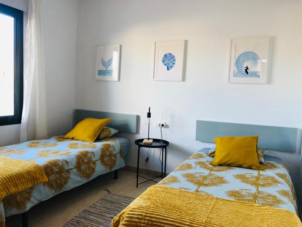 a bedroom with two beds with yellow pillows at Casa Gara in Yaiza