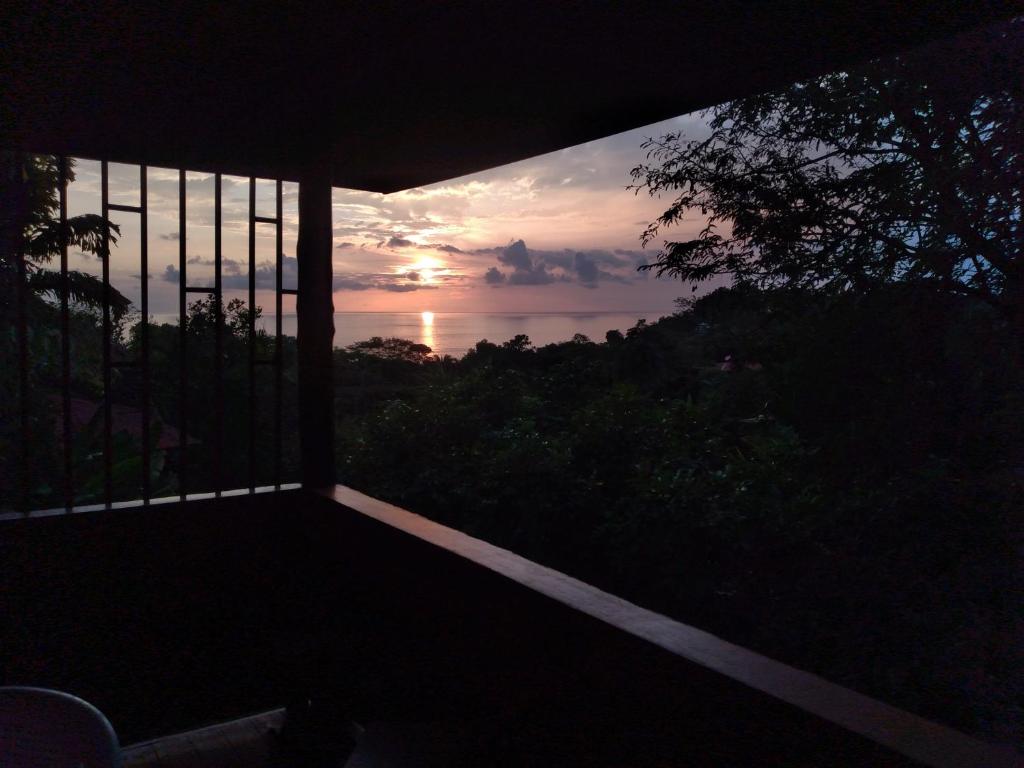 uma vista para o pôr-do-sol a partir de uma varanda de uma casa em Casa Miramar em Uvita