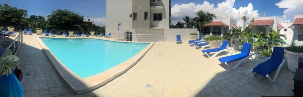 una gran piscina con sillas azules junto a un edificio en Boca del Mar Residence, Boca Chica en Boca Chica