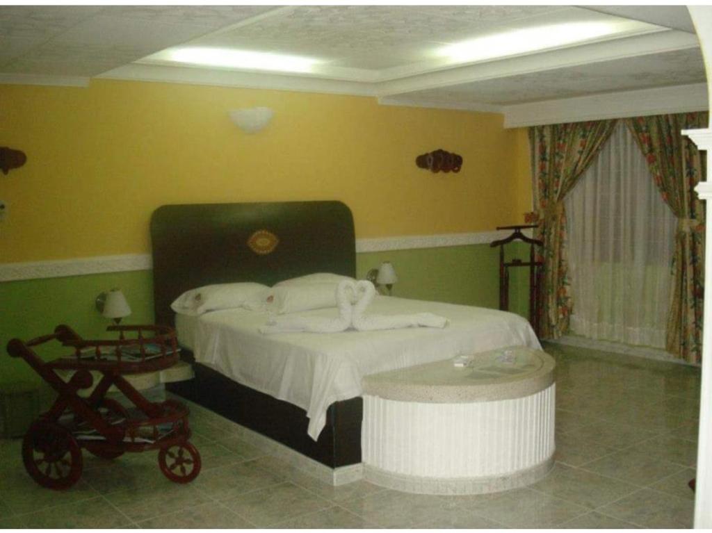 ein Schlafzimmer mit einem Bett und einem Kinderwagen in der Unterkunft Aparta Hotel Plenitud in Palmira