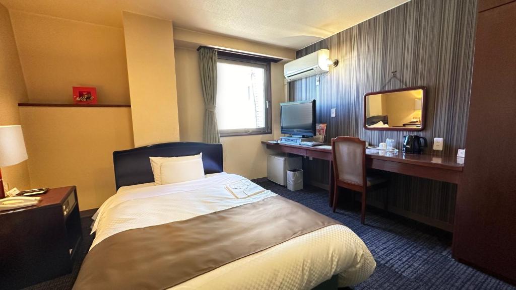 a hotel room with a bed and a desk with a computer at Hotel Honjo in Honjo